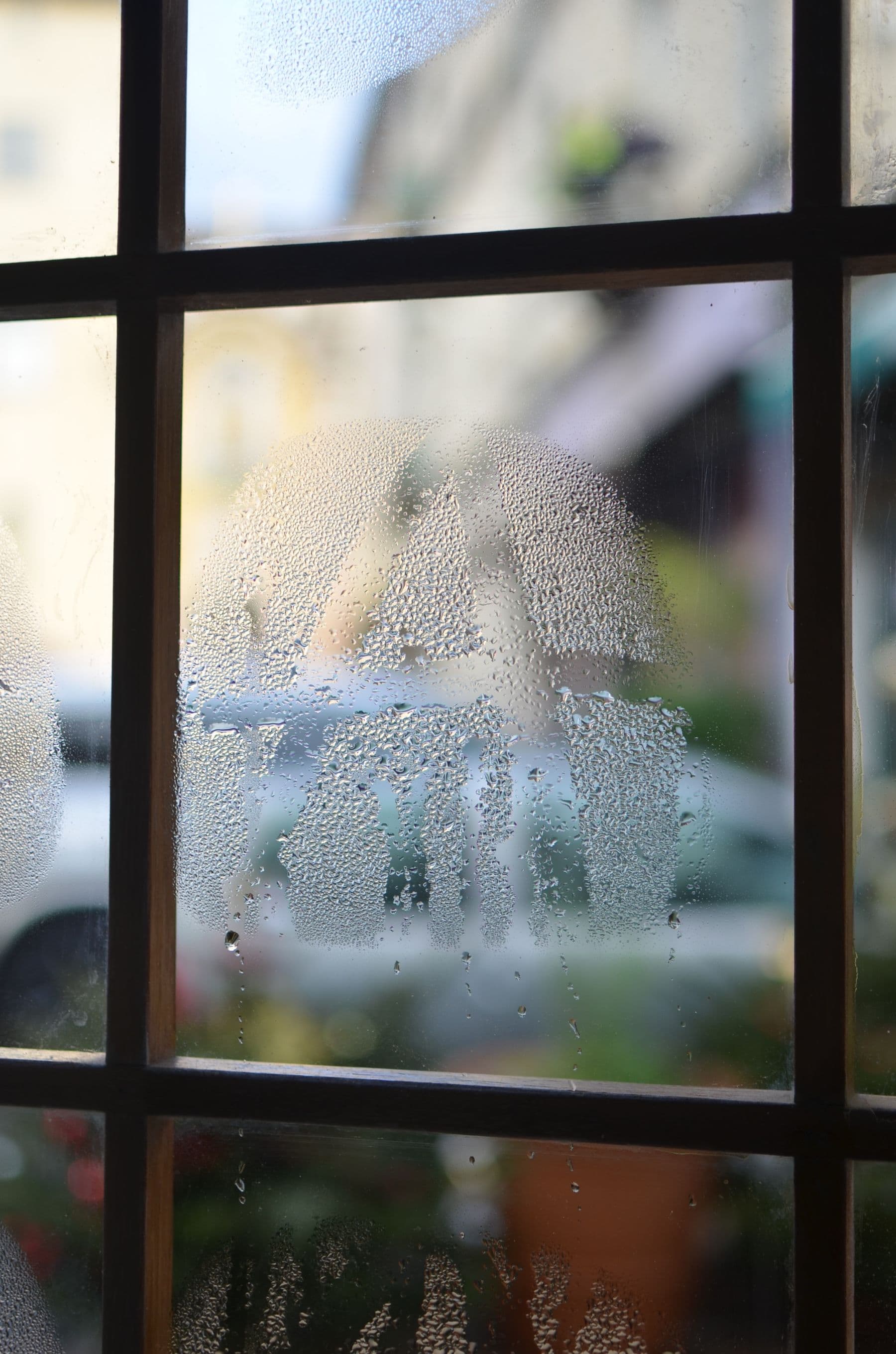 Cristal empañado con gotas de condensación en una ventana de cuarterones